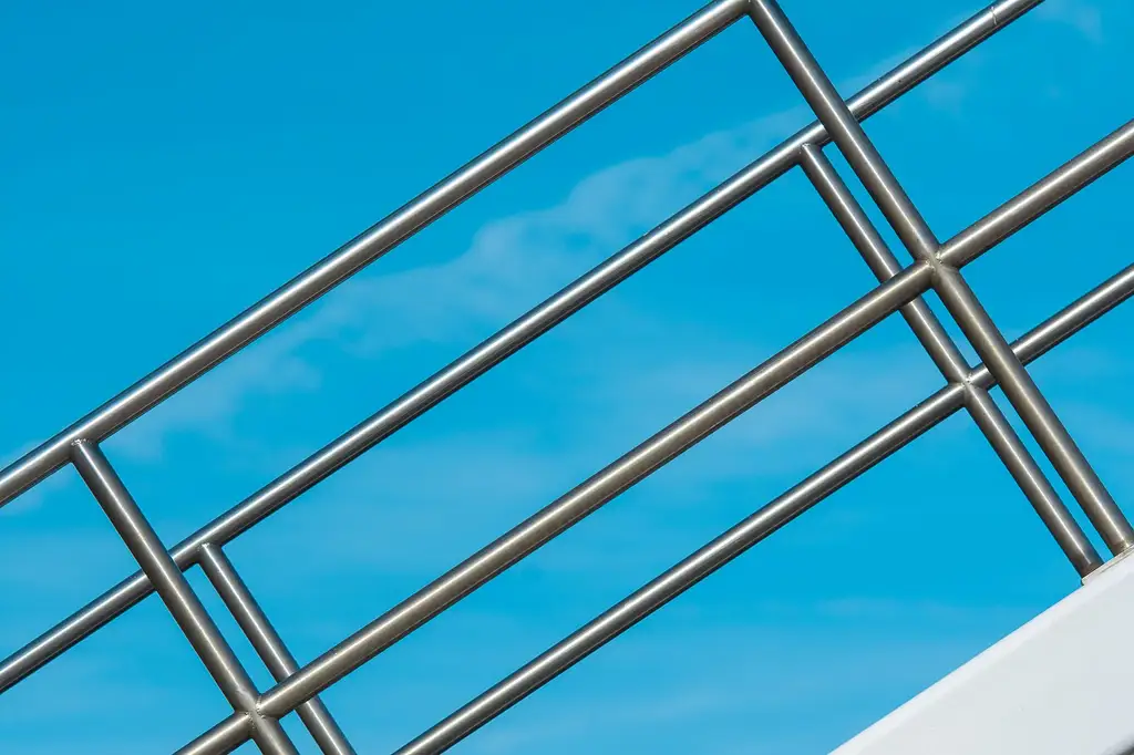 A stainless steel handrail and infill bars seen against open sky